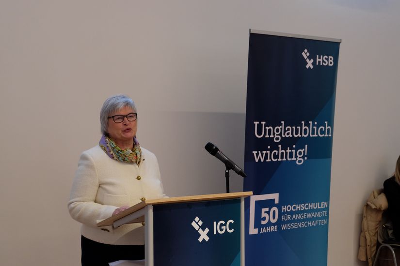 Frau steht an Stehpult und h&auml;lt eine Rede.