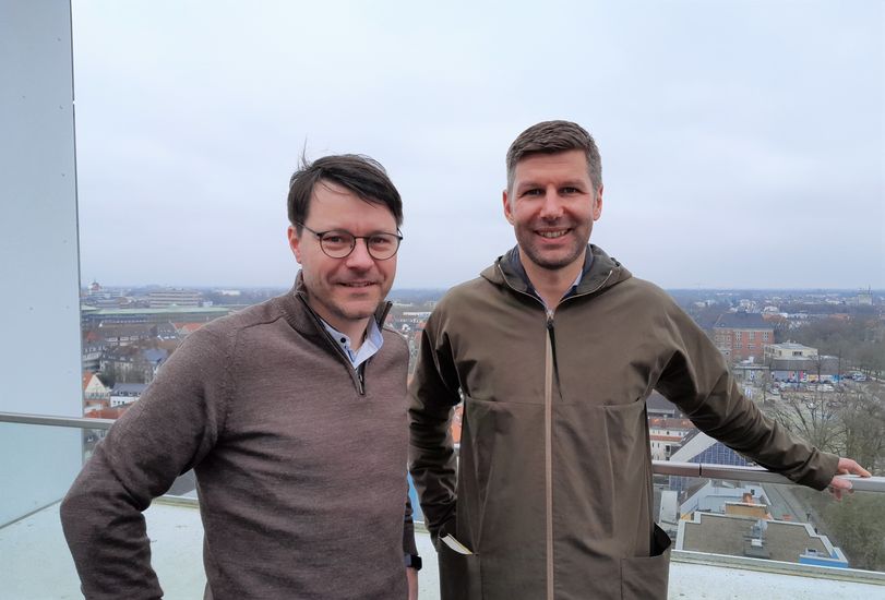 Zwei M&auml;nner lachen in die Kamera