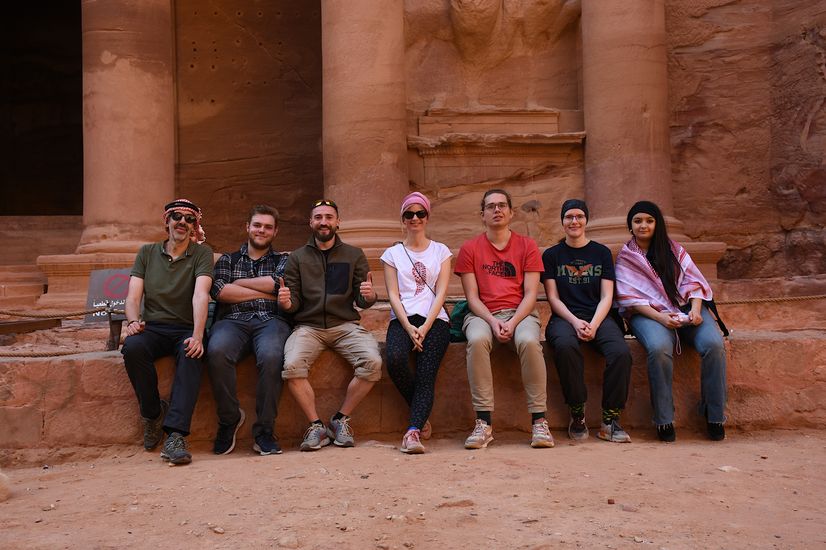 Studierende und Betreuer sitzen vor dem Treasury Tempel in Petra, Dieser Tempel ist in einen Felsen eingeschlagen