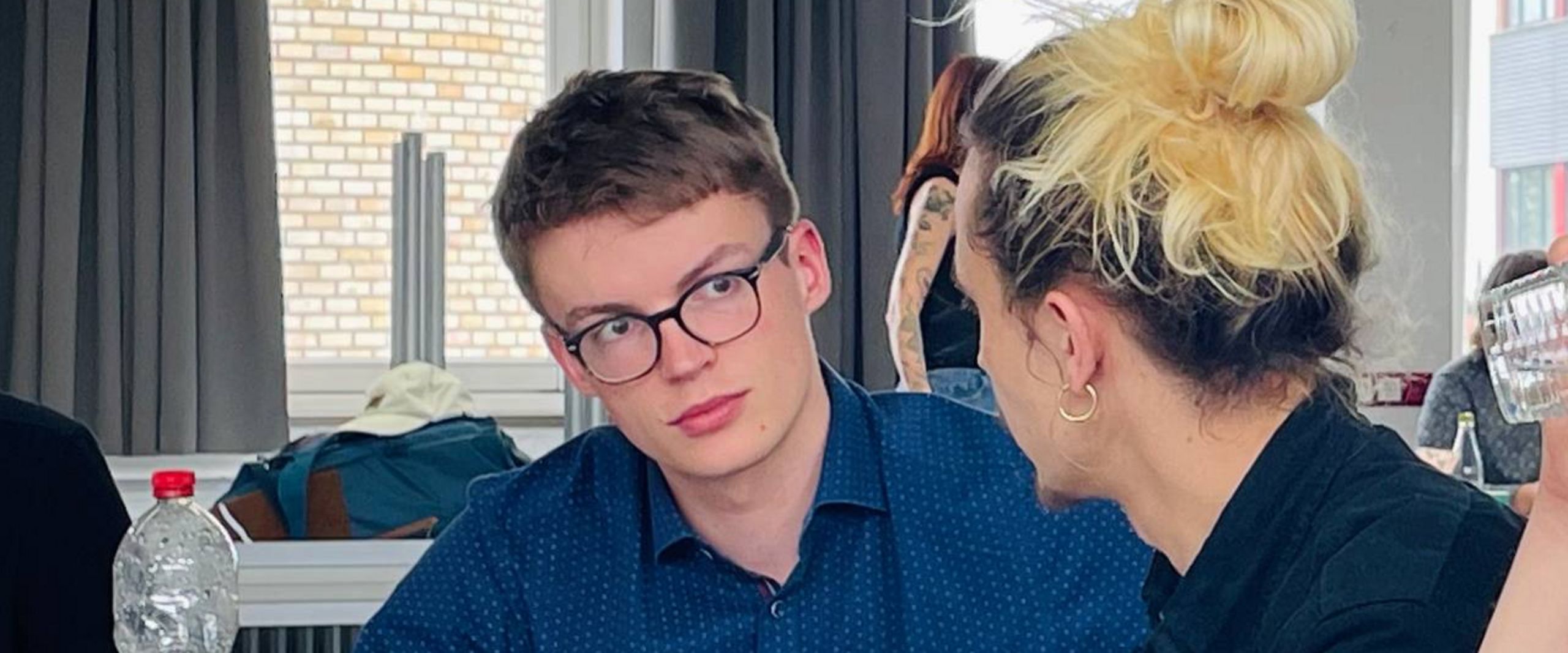 Auf dem Bild sind zwei Studierende zu sehen, die sich über etwas unterhalten. 