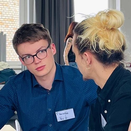 Auf dem Bild sind zwei Studierende zu sehen, die sich &uuml;ber etwas unterhalten. 