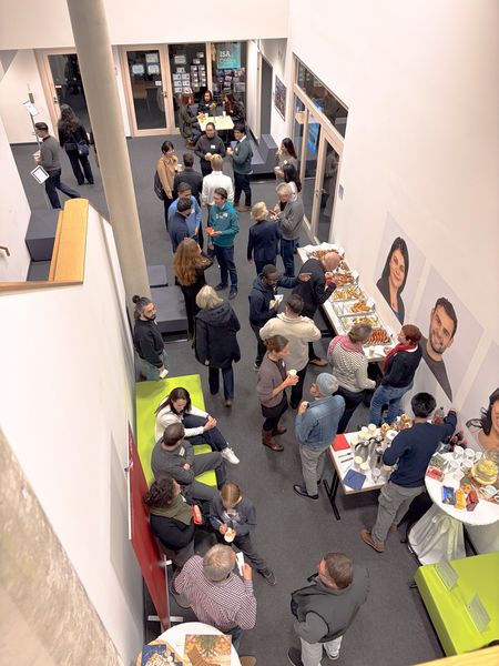 viele Alumni stehen in einem Raum mit Snacks und Getr&auml;nken