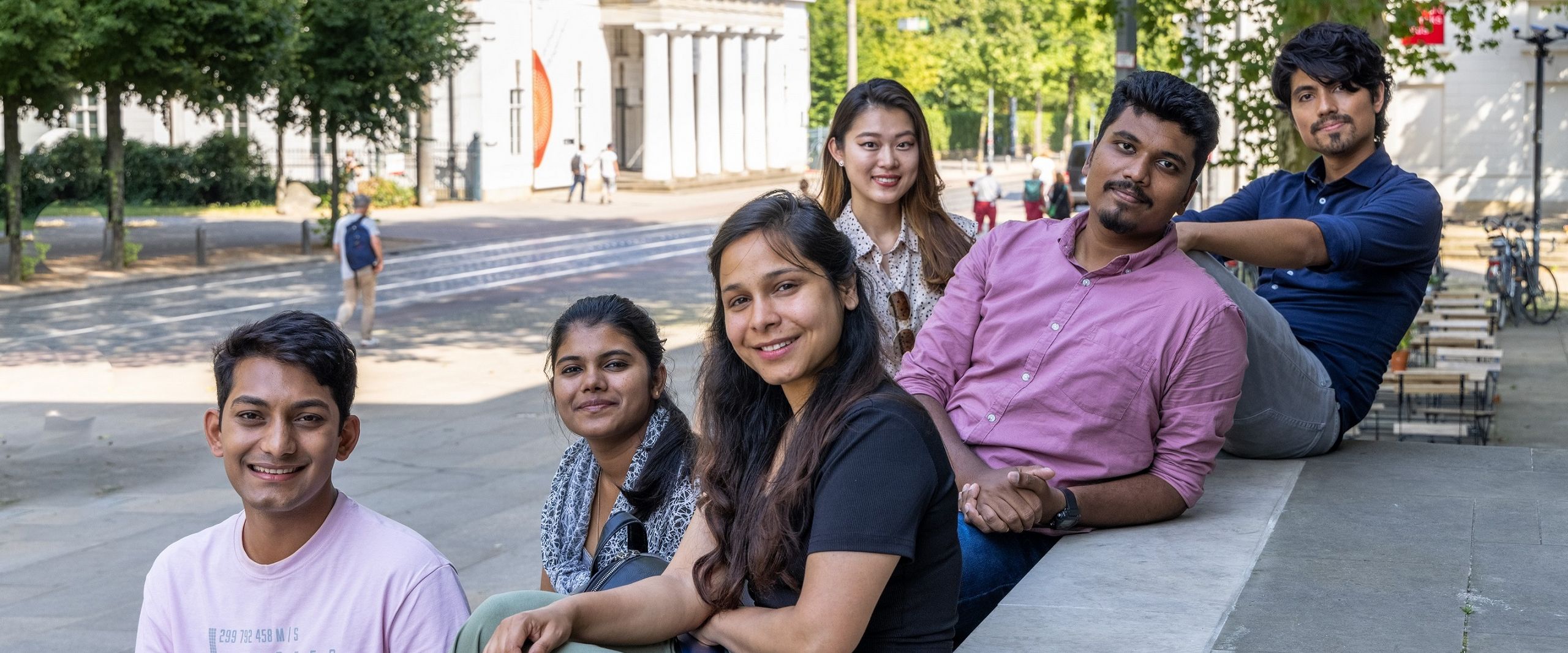 Studierende International Graduate Center Sechs junge Menschen sitzen und stehen zusammen an einer Treppe. Im Hintergrund sieht man eine Straße und Häuser in Bremen.ch