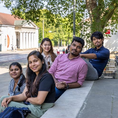 Sechs junge Menschen sitzen und stehen zusammen an einer Treppe. Im Hintergrund sieht man eine Stra&szlig;e und H&auml;user in Bremen.ch