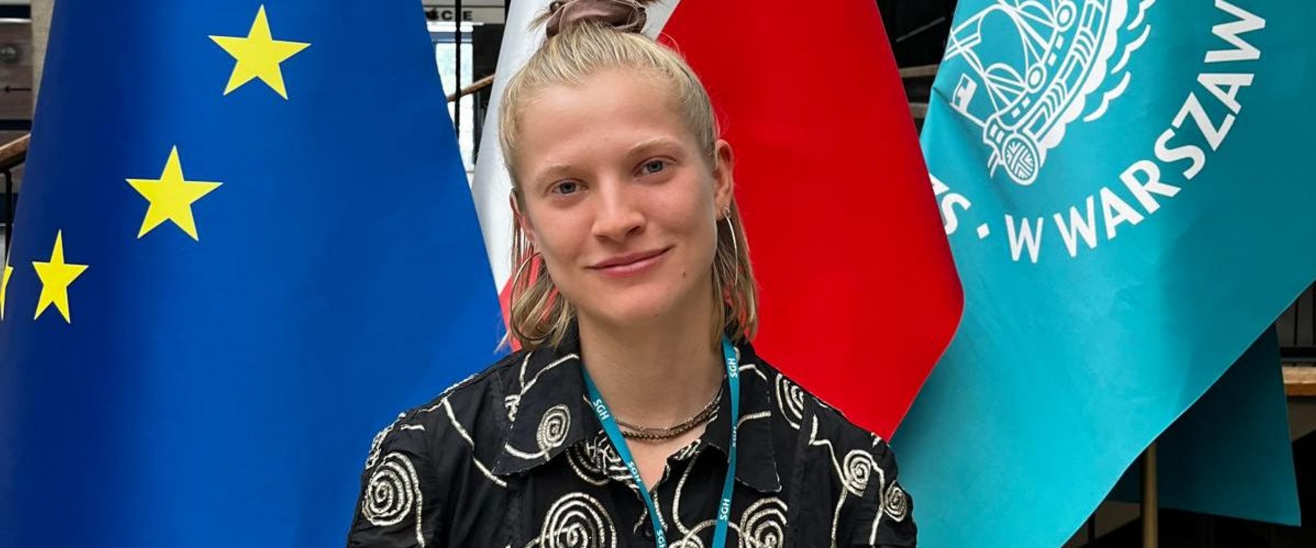 Junge Frau steht vor drei Fahnen