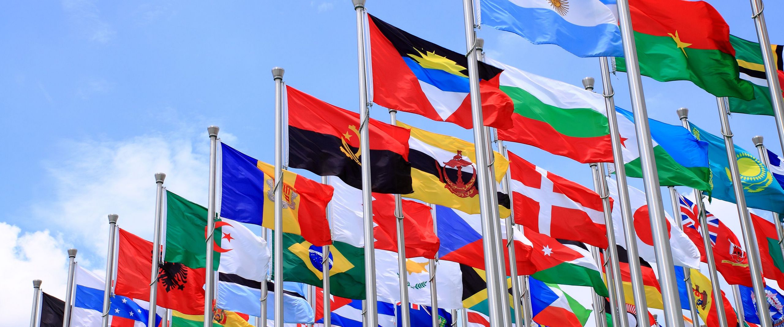 Flaggen verschiedener Länder vor blauem Himmel