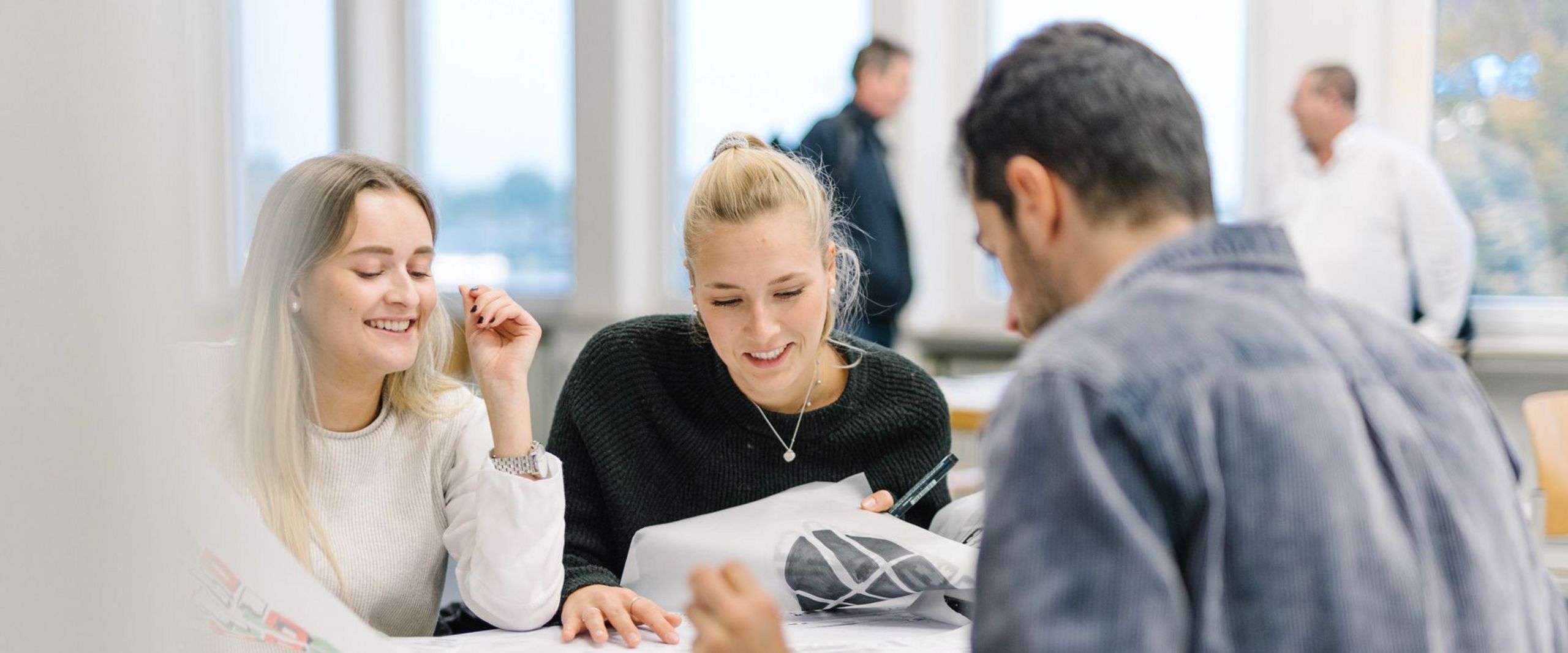 Workshop Urban Cities Drei Studierende sitzen bei einer Gruppenarbeit zusammen an einem Tisch