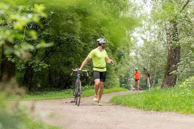 Läufer:innen sprinten die Strecke entlang und schieben gleichzeitig ein Fahrrad.