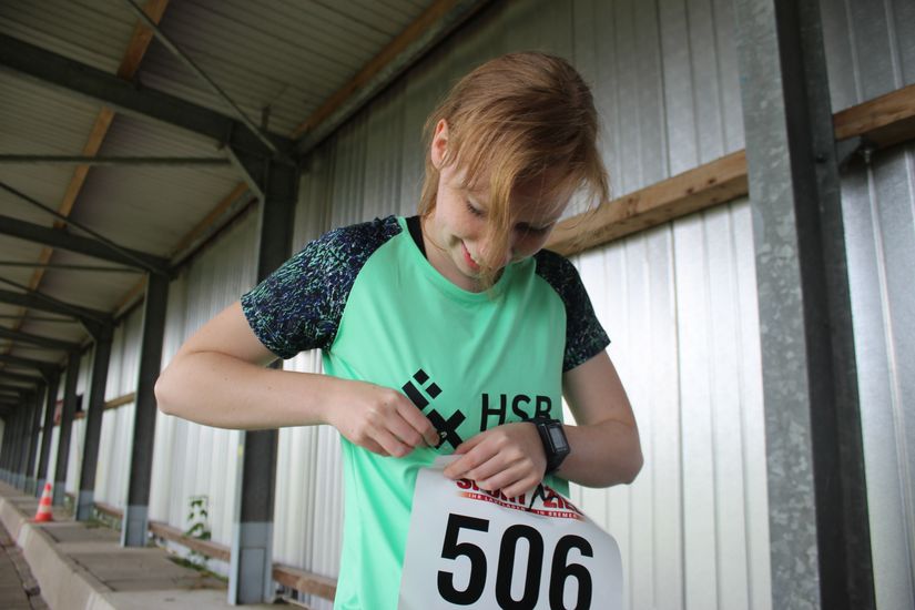 Eine L&auml;uferin macht sich ihr Schild mit Nummer von dem T-Shirt ab.