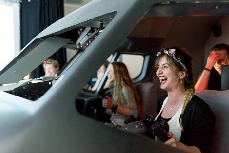 Studierende lachend im Flugsimulator.