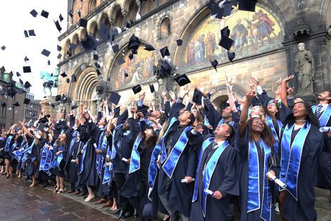 Absolvent:innen in Talar werfen die H&uuml;te in die Luft