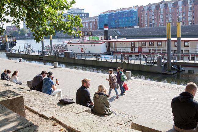 Leute sitzen an der Schlachte mit Blick auf die Weser