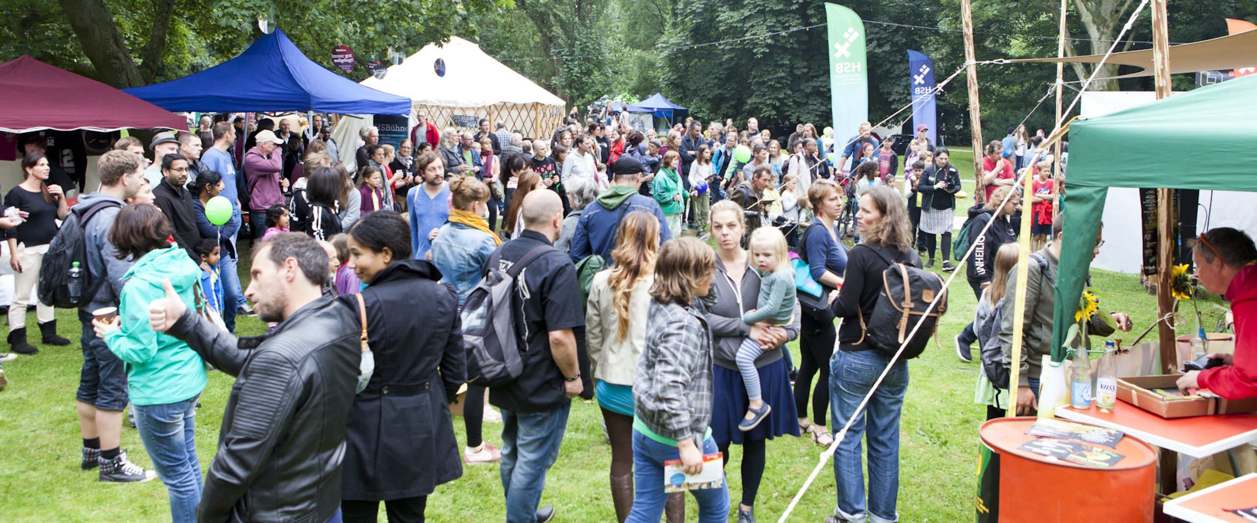 Summersounds Menschen laufen über eine Wiese. Um sie herum stehen Zelte.