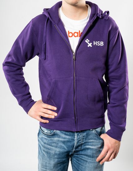 Das Model trägt eine violette Sweatshirtjacke für Herren mit dem HSB-Logo darauf.