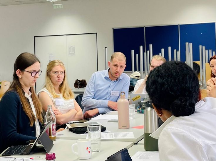 Auf dem Bild sind Studierende zu sehen, die in Verhandlungen stehen. Zwei beteiligte Personen scheinen über das aktuell besprochene nicht erfreut zu sein. 