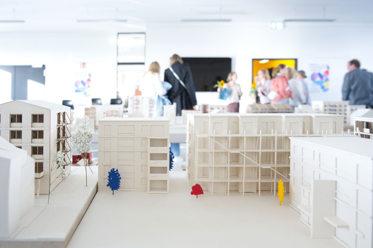 Architekturmodell mit mehrst&ouml;ckigen H&auml;usern. Im Hintergrund sieht man unscharf Menschen.