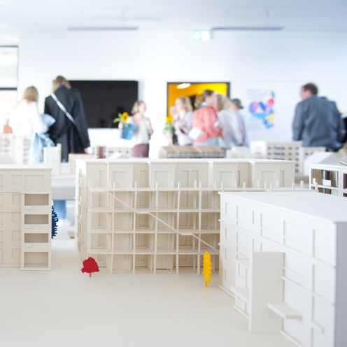 Architekturmodell mit mehrst&ouml;ckigen H&auml;usern. Im Hintergrund sieht man unscharf Menschen.