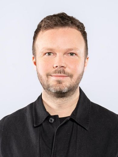 Auf dem Bild ist Philipp Quack zusehen. Er hat kurze braune Haare und einen Dreitagebart. Er tr&auml;gt ein schwarzes Hemd. 