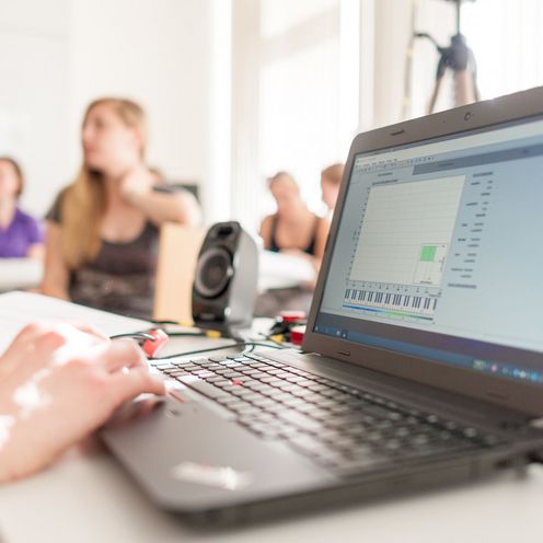 Laptop und Studierende unscharf im Hintergrund