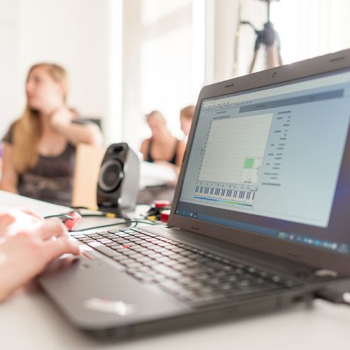 Laptop und Studierende unscharf im Hintergrund