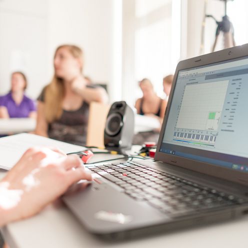 Laptop und Studierende unscharf im Hintergrund