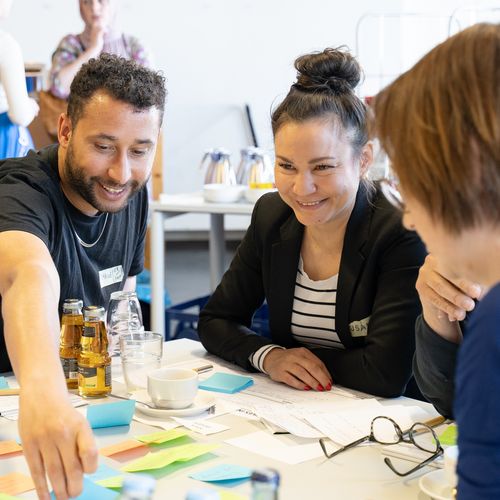 Mann und zwei frauen sitzen am Tisch und interagieren miteinander