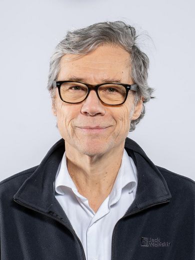 Auf dem Bild ist Martin Speth zusehen. Er hat kurzes graues Haar. Er tr&auml;gt eine Brille und ein hellblaues Hemd unter einer schwarzen Strickjacke. 