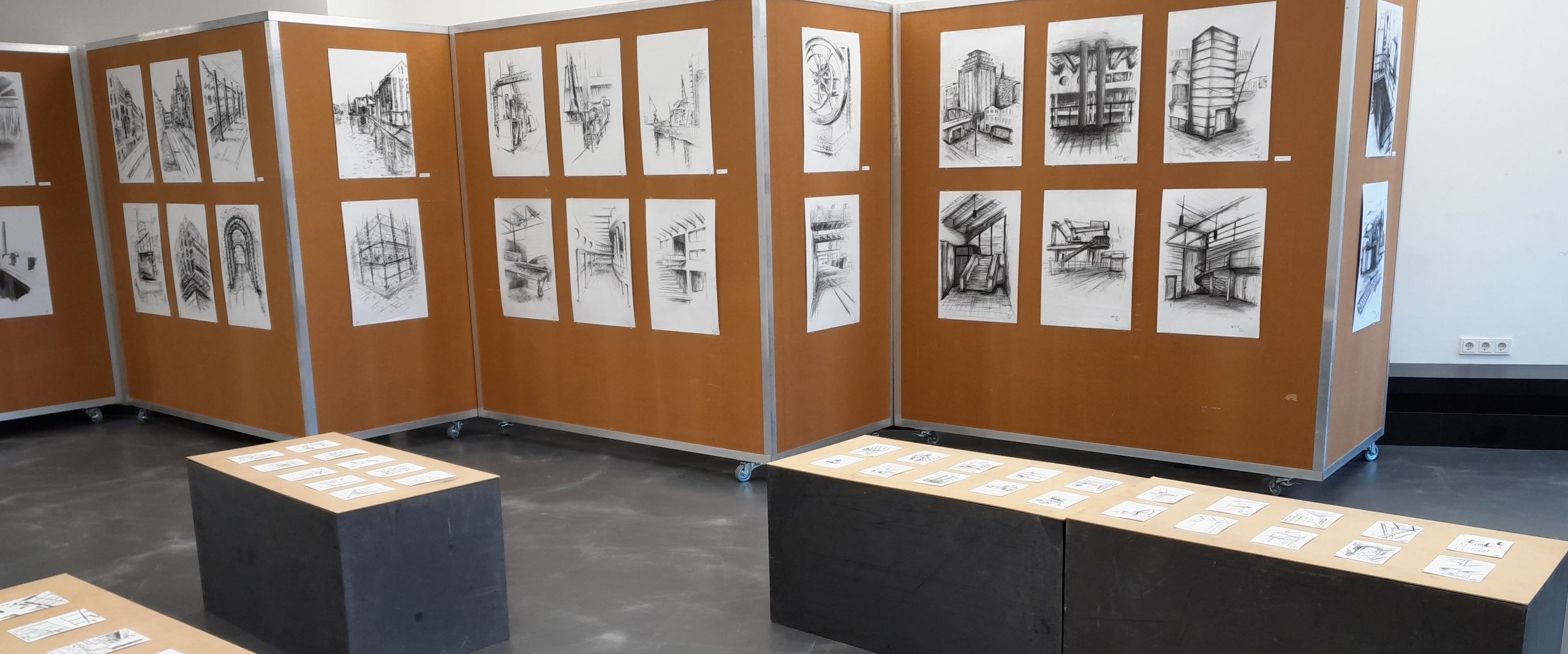 Raum mit Kohelzeichnungen an Stellwänden und Bänken