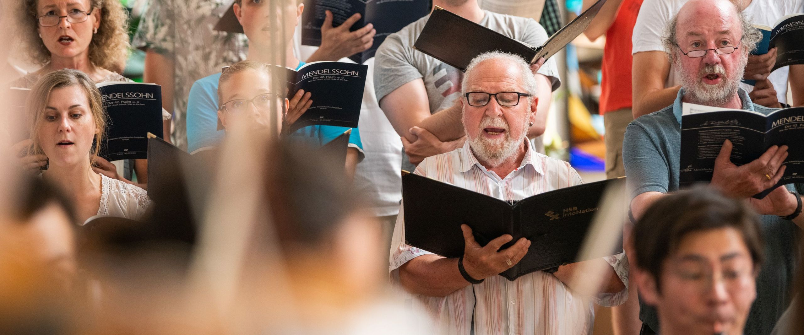 Männer und Frauen singen mit Notenbüchern in der Hand