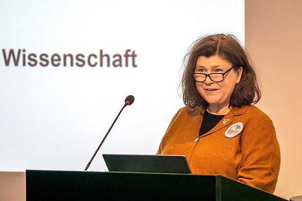 Frau mit Brille h&auml;lt Rede am Podium