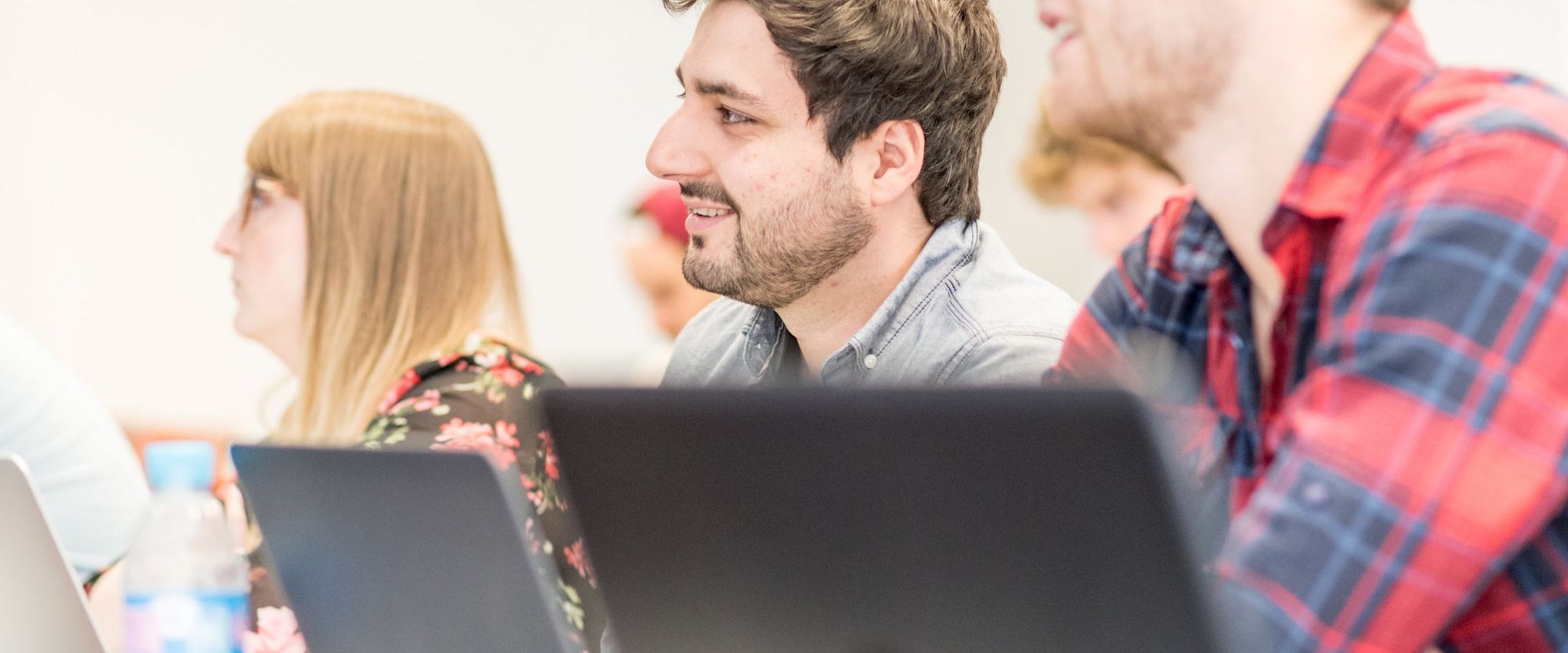 Studierende vor Laptops hören eine Vorlesung. 