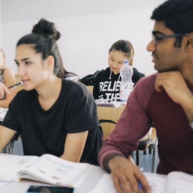 Eine Gruppe Studierender sitzt an Tischen in einem Seminarraum.