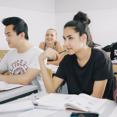 Eine Gruppe Studierender sitzt an Tischen in einem Seminarraum.