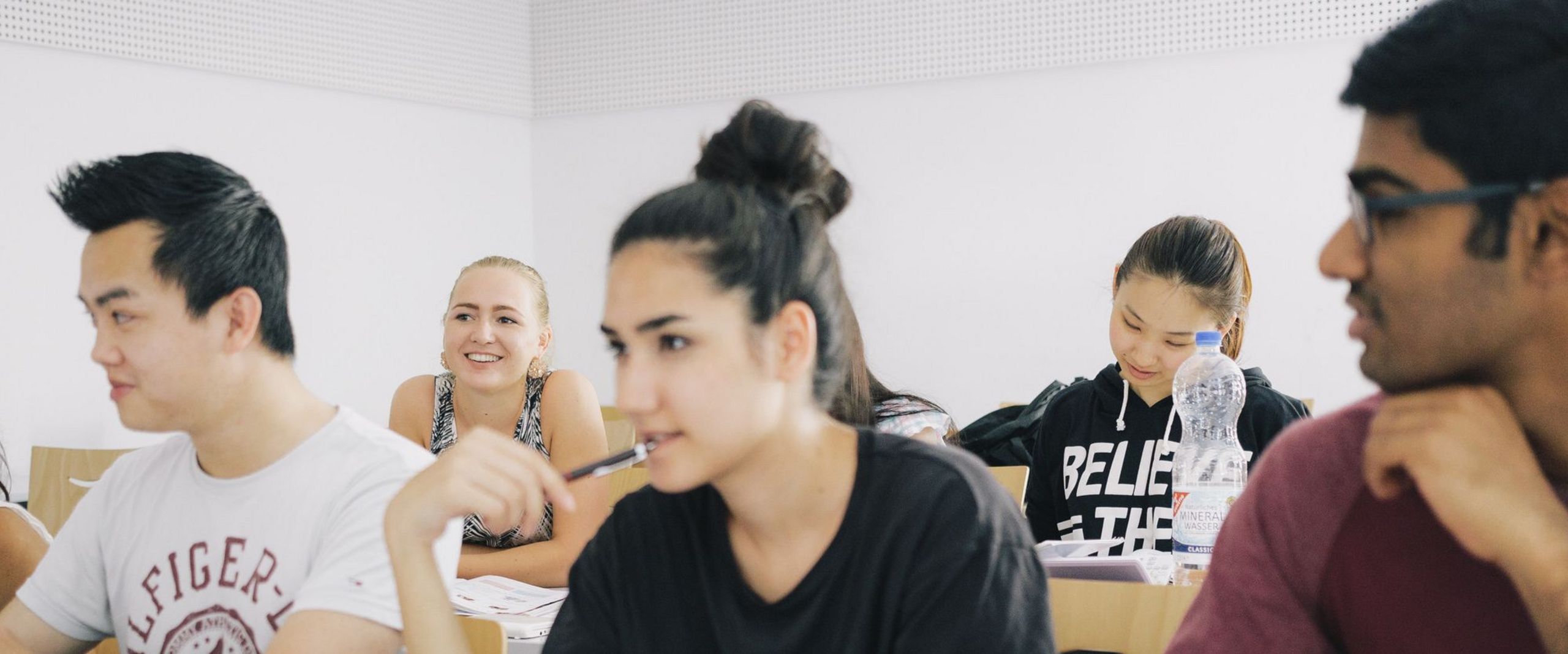 Eine Gruppe Studierender sitzt an Tischen in einem Seminarraum.