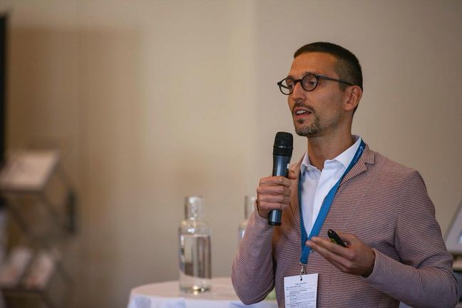 Dr. Giacomo Rossettini hält ein Mikrofon in der Hand und spricht in das Mikrofon