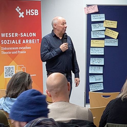 In einem Seminarraum stehen ein Mann und eine Frau vor 2 Pinw&auml;nden und diskutieren mit dem gemischten Publikum.