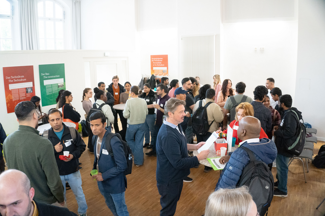 Studierende und Unternehmen sprechen miteinander in einem großen Raum