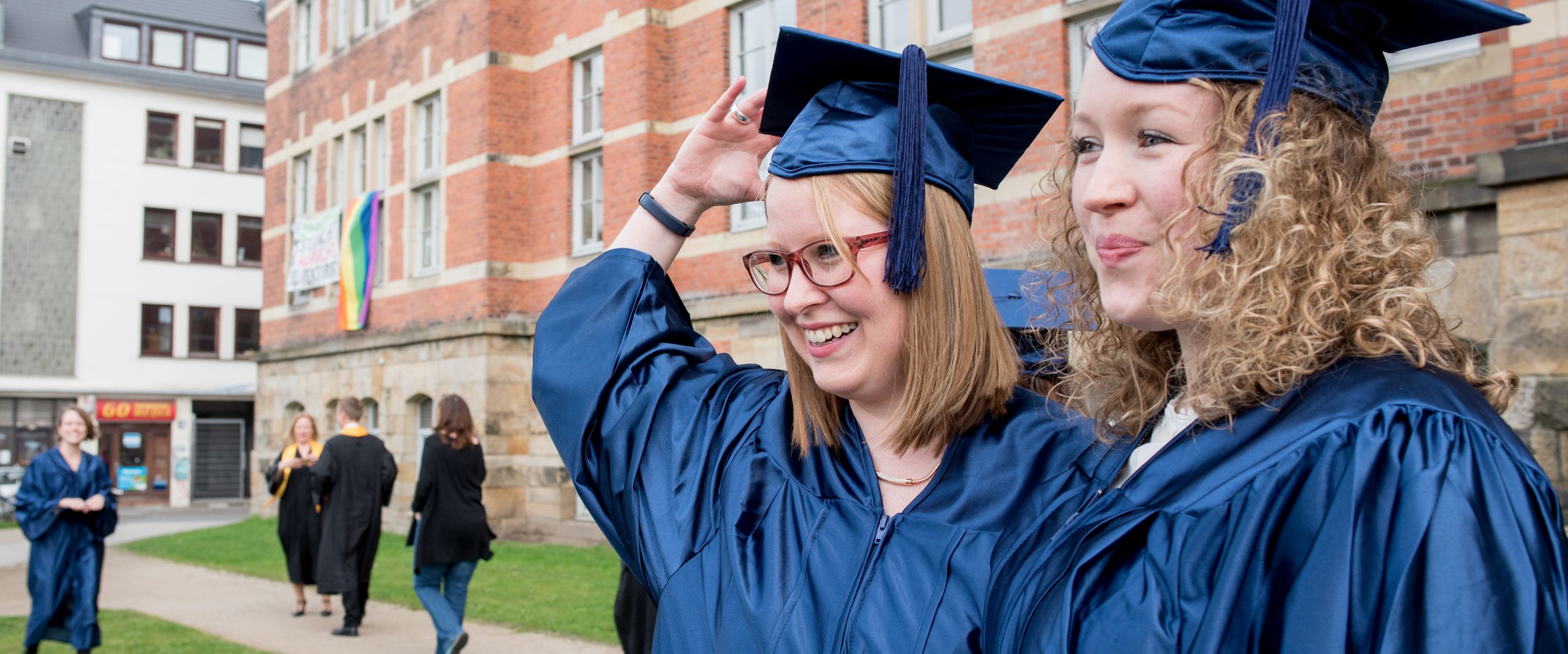 Zwei Abolventinnen vor M Gebäude in Talaren
