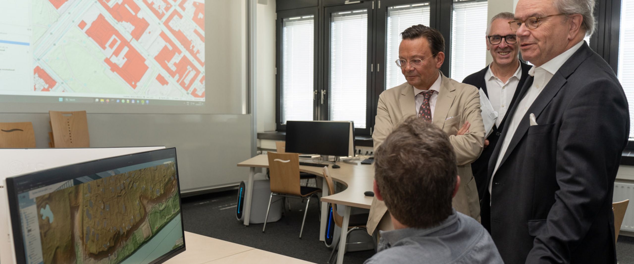 hegemann Stiftung labor Drei Männer stehen an einem Schreibtisch. daran sitzt ein Mann an einem Bildschirm mit dem Rücken zur Kamera. An der Wand sieht man eine Grafik.