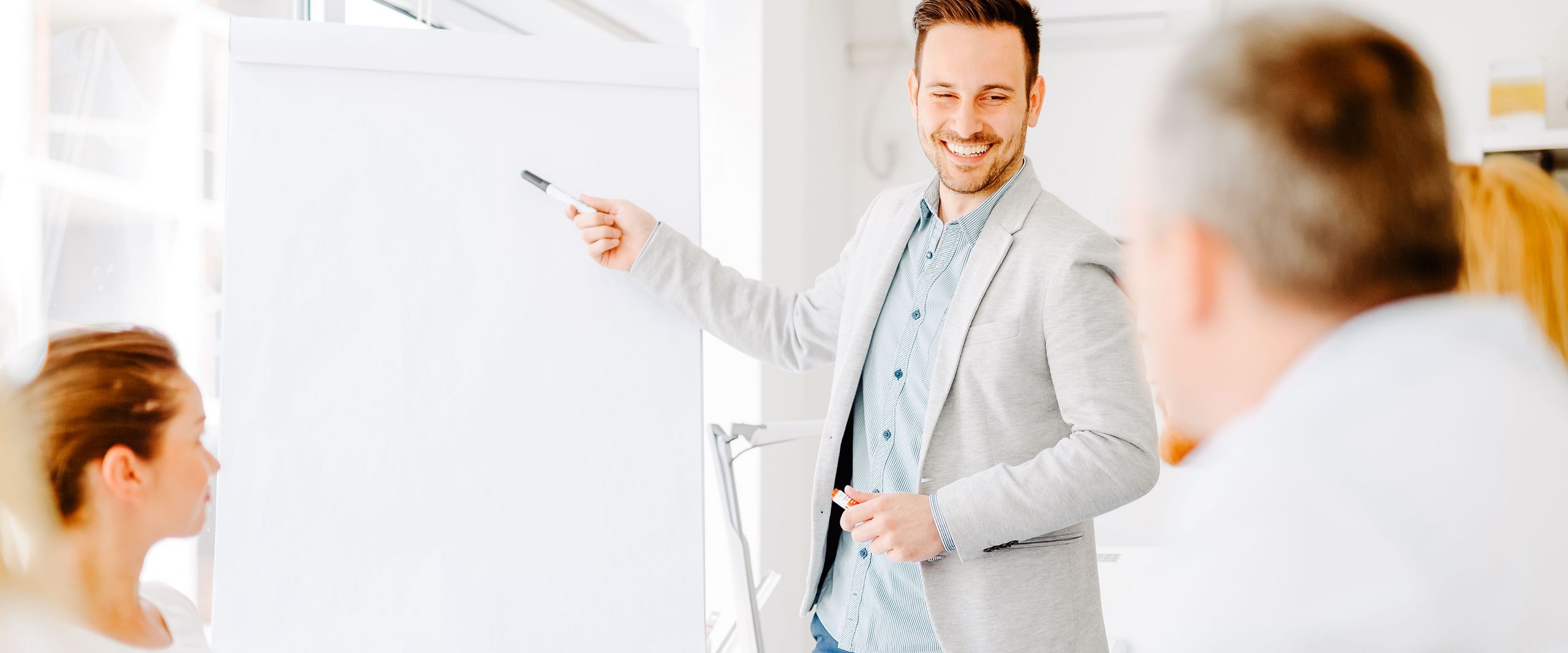 Mann erklärt seinem Team etwas am Flipchart