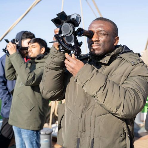 M&auml;nner auf einem Segelschiff schauen durch Sextanten.