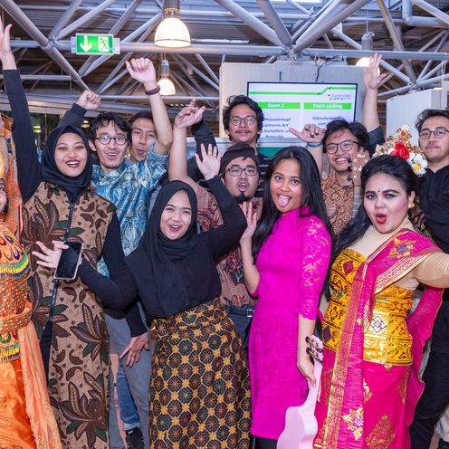 Eine Gruppe Studierender posiert in bunter traditioneller ostasiatischer Kleidung.