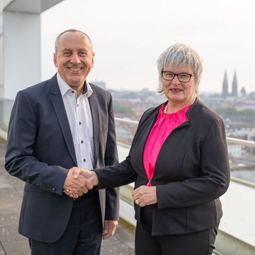 Mann und Frau geben sich die Hand und l&auml;cheln in die Kamera. Sie stehen auf einer Dachterrasse. Im Hintergrund sieht man die Kulisse der Innenstadt von Bremen