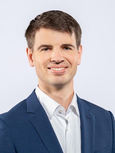 Auf dem Foto ist Florian vom Lehn zusehen. Er hat kurze braune Haare und tr&auml;gt ein wei&szlig;es Hemd unter einem blauen Sakko.