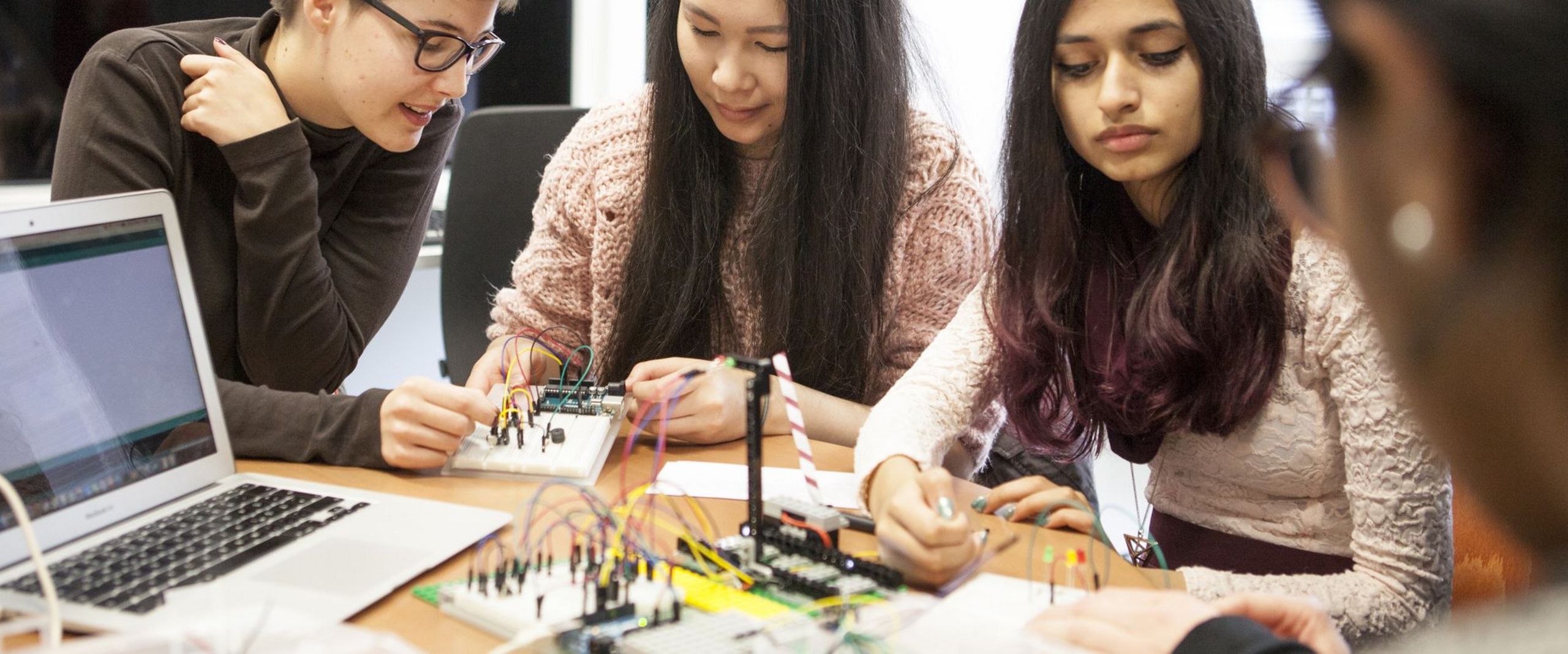 Studentinnen bauen ein technisches Gerät. 