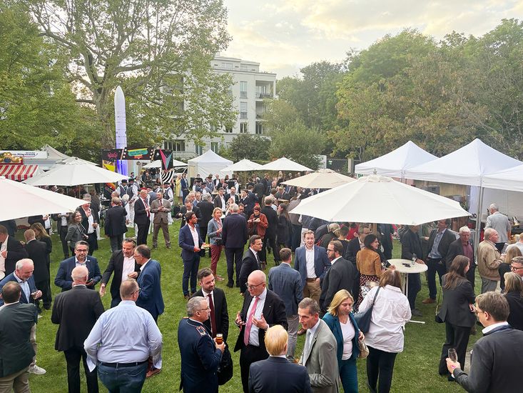 Blick auf ein Gartenfest mit vielen Menschen und Pavillons.