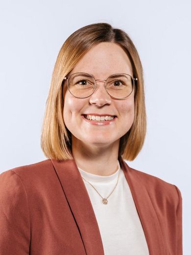 Auf dem Bild ist Jennifer Pebdani zu sehen. Sie hat schulterlanges, rotblondes Haar und trägt ein weißes Shirt unter einem rostfarbenen Blazer. 