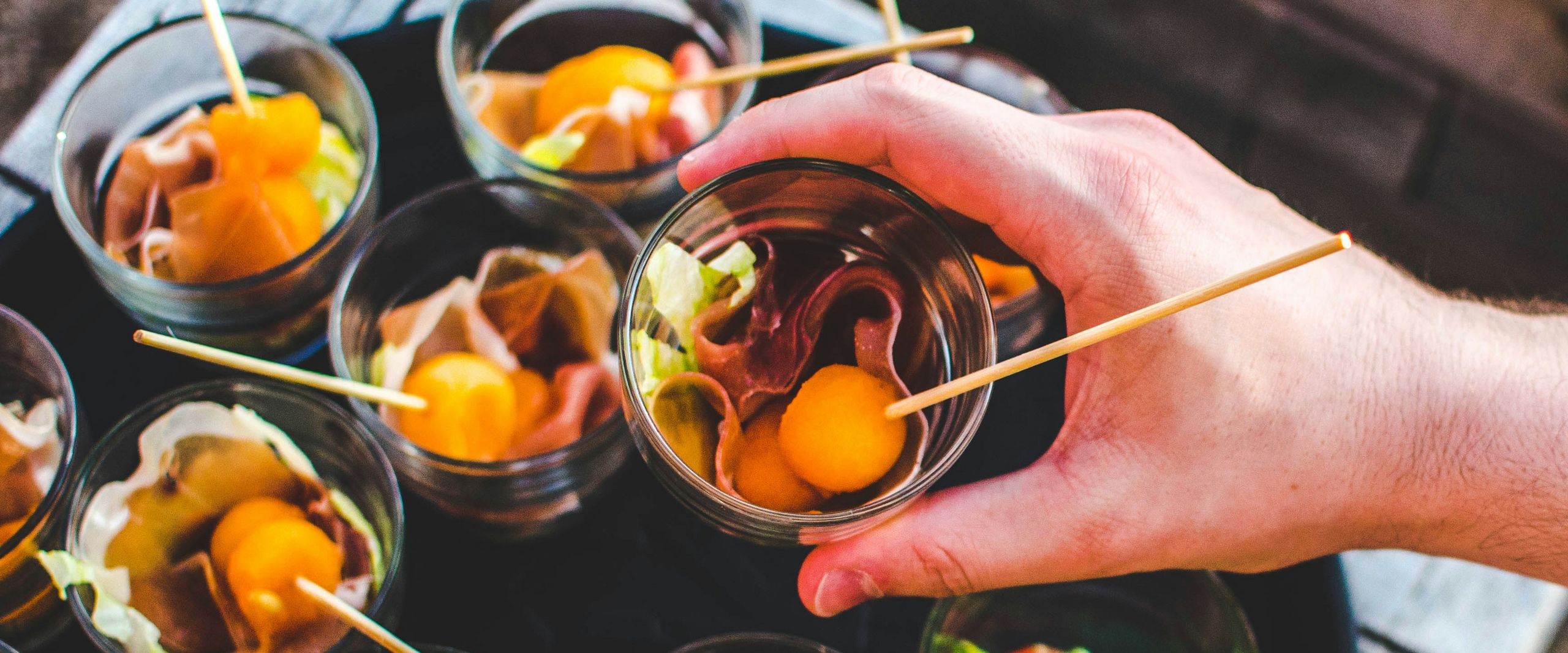 Nahaufnahme einer Hand, die Essensh&auml;ppchen auf einem Teller arangiert.