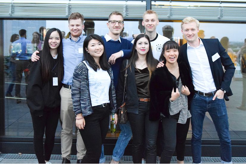 Studierende posieren vor einer Fensterfront.