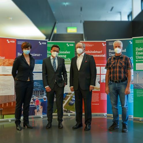 4 Personen mit Maske vor Rollups 